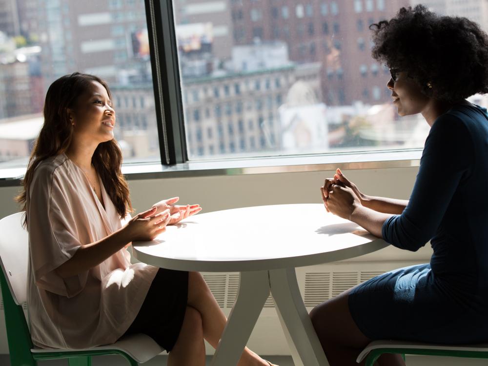 twee vrouwen aan een tafel die in gesprek zijn